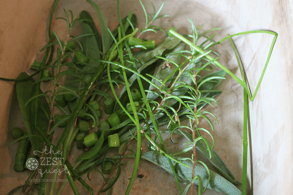 Sage-Rosemary-Chives-Garlic-Scapes-layered-in-clay-baker-for-herbed-pork-roast-2-The-Zest-Quest
